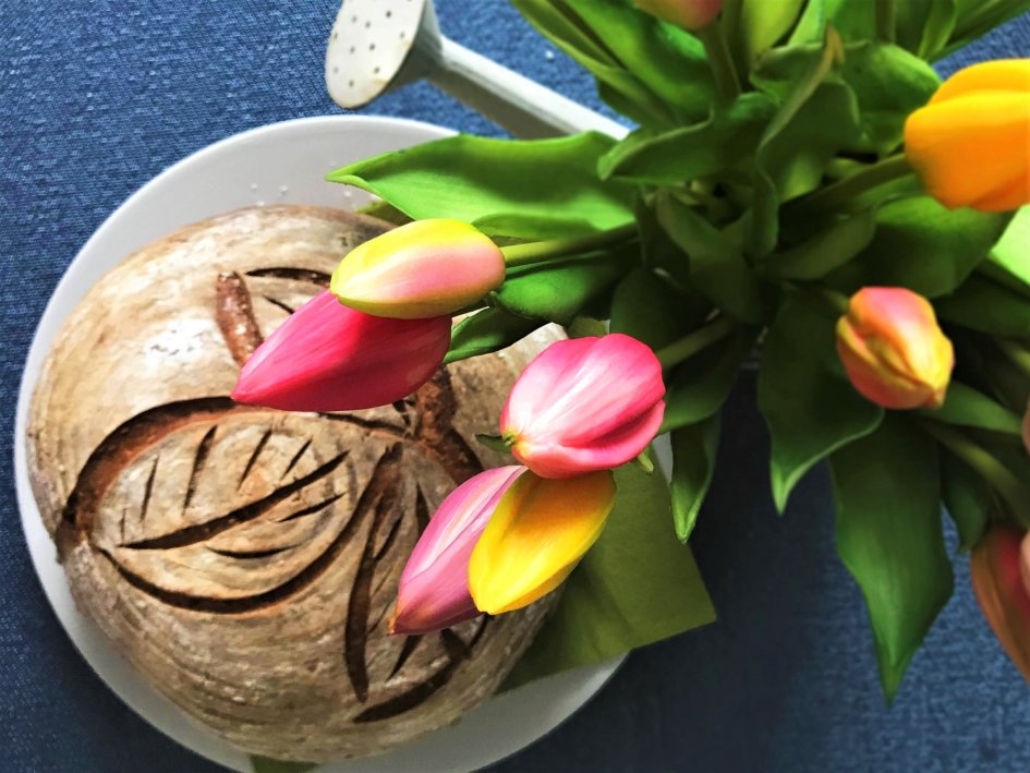 kváskový chlieb položený na stole a kytica tulipánov